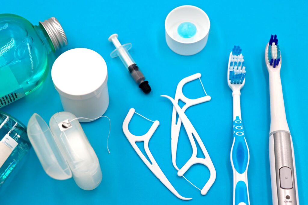 Mouthwash, dental floss, and toothbrushes arranged on a blue background