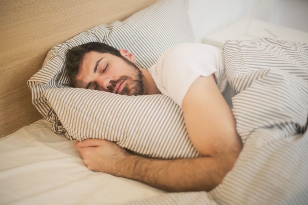 Man sleeping on his side in bed with striped bedding